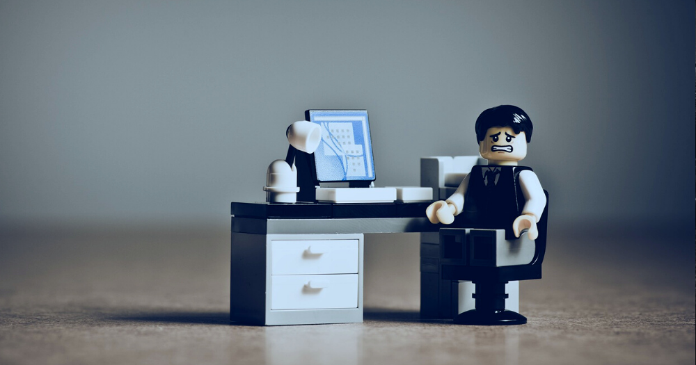 I'm taking time off work. Pictured: a stressed Lego man alone at a Lego desk in a office
