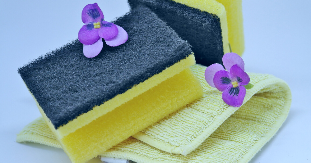 A day of house work. Pictured: sponges, a washcloth and purple flowers