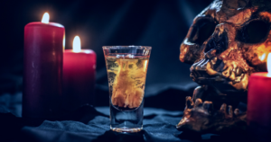 Hallowe'en hangover. Pictured: lit candles, a potion in a shot glass and a skull