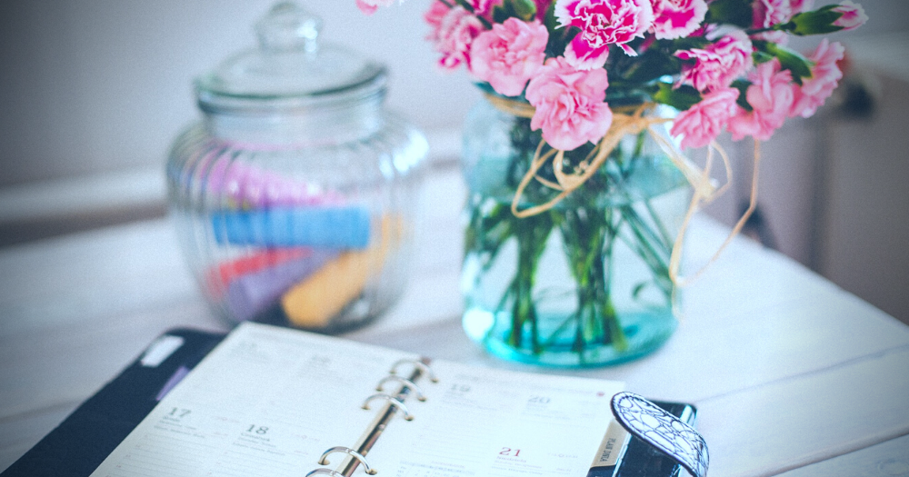 Time for a routine. Pictured: a day-planner, a vase of flowers and a clear jar of chalk